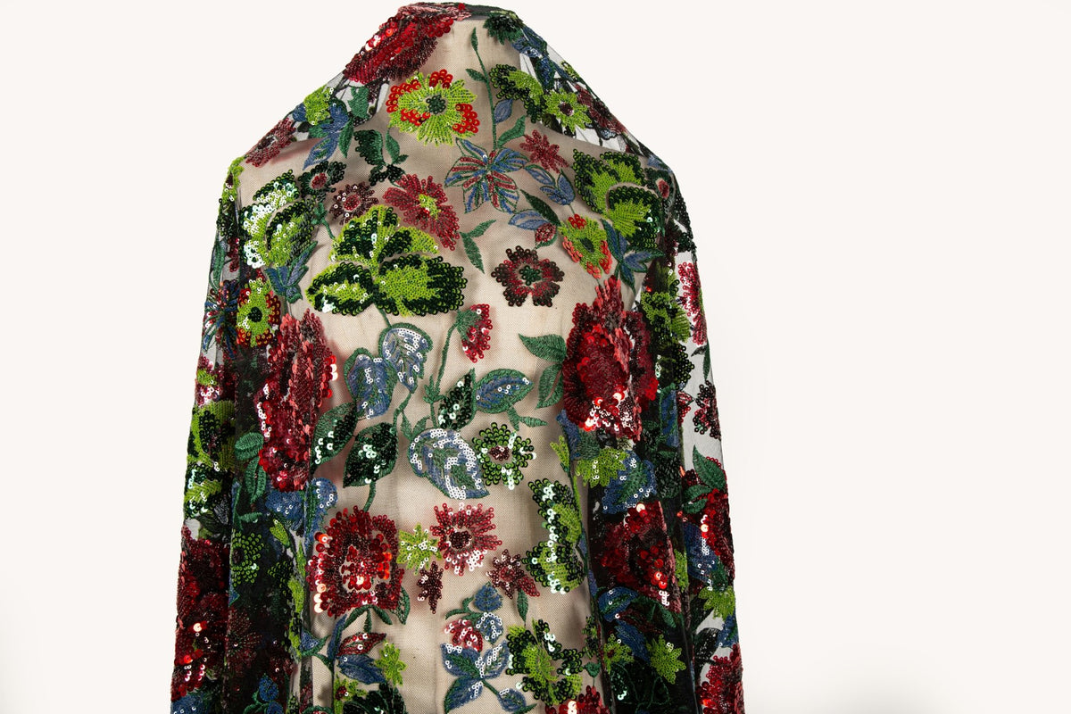 A sequin floral embroidery fabric on a black base, with red and green motifs.