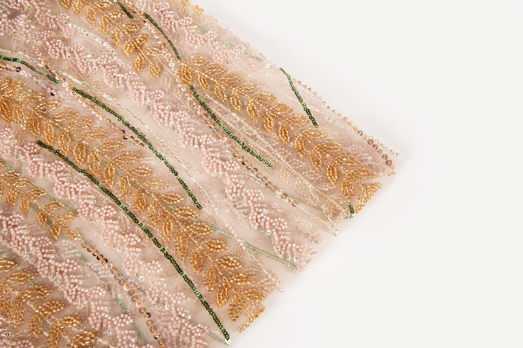 A hand-beaded embroidery fabric, with a vertical, wavy pattern of laurel leaves in rose gold, pink, and green.
