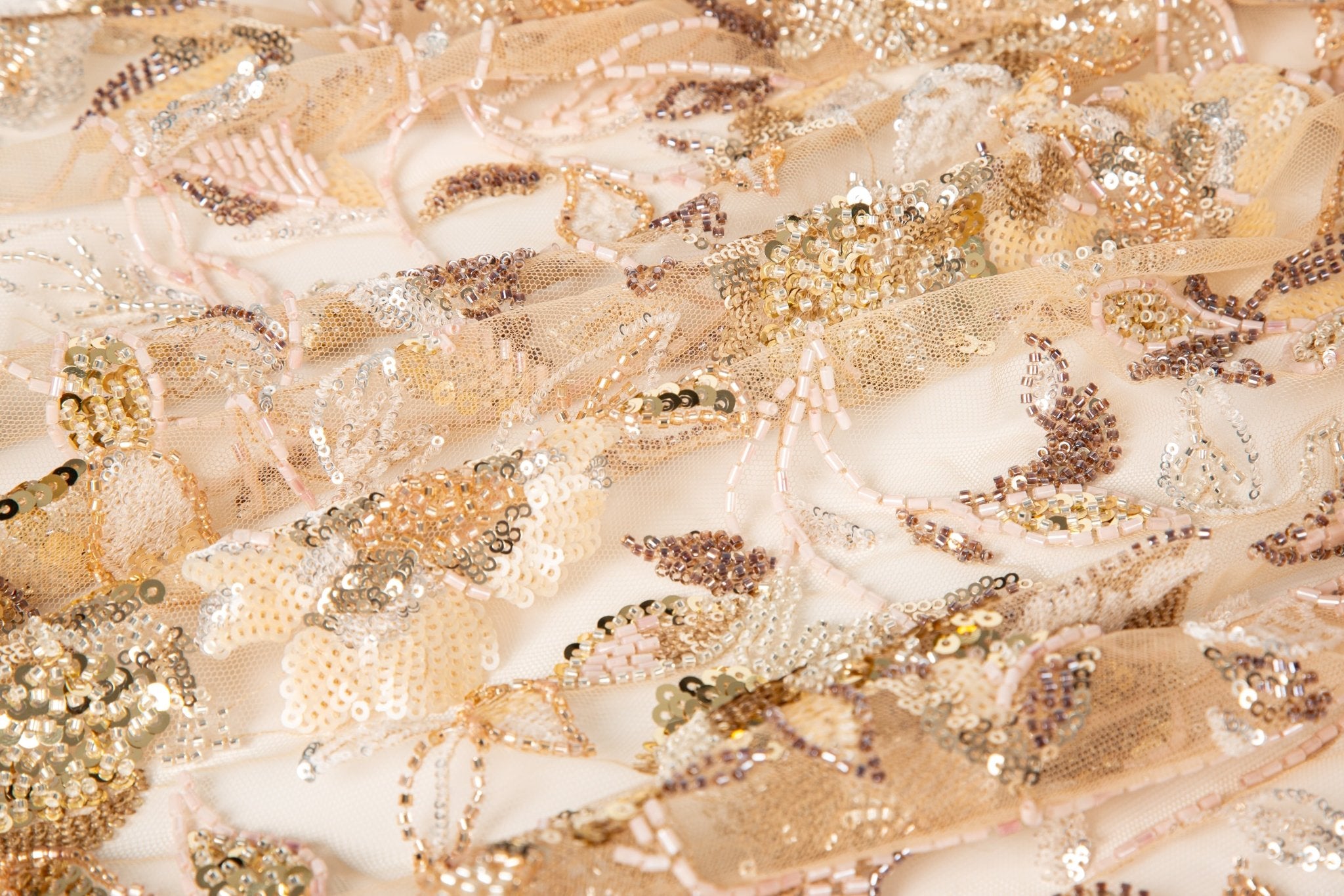 A luxurious beaded embroidery fabric, with a dense, trailing floral vine pattern in a warm rose gold and pink palette.
