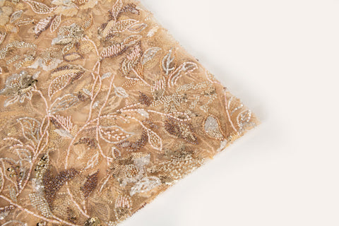 A luxurious beaded embroidery fabric, with a dense, trailing floral vine pattern in a warm rose gold and pink palette.
