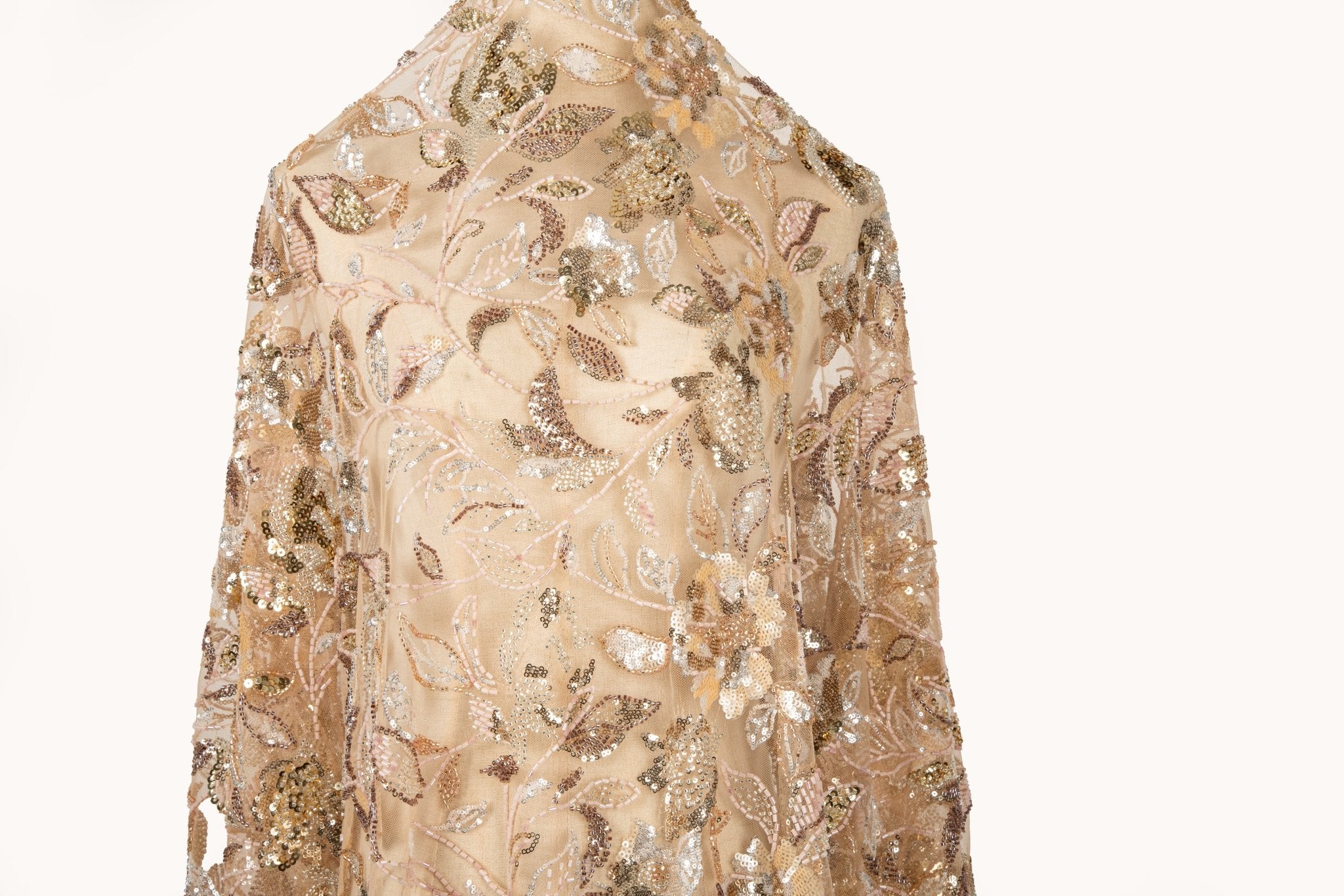 A luxurious beaded embroidery fabric, with a dense, trailing floral vine pattern in a warm rose gold and pink palette.
