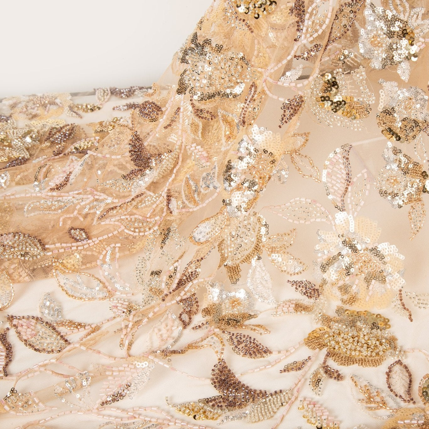 A luxurious beaded embroidery fabric, with a dense, trailing floral vine pattern in a warm rose gold and pink palette.
