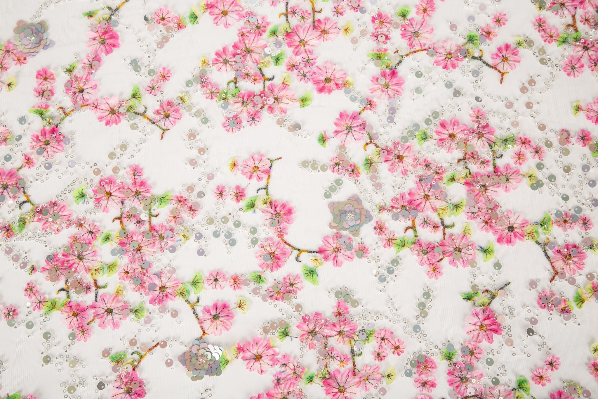 A fine embroidery fabric on white tulle, with a pattern of pink cherry blossom branches and shimmering sequins.
