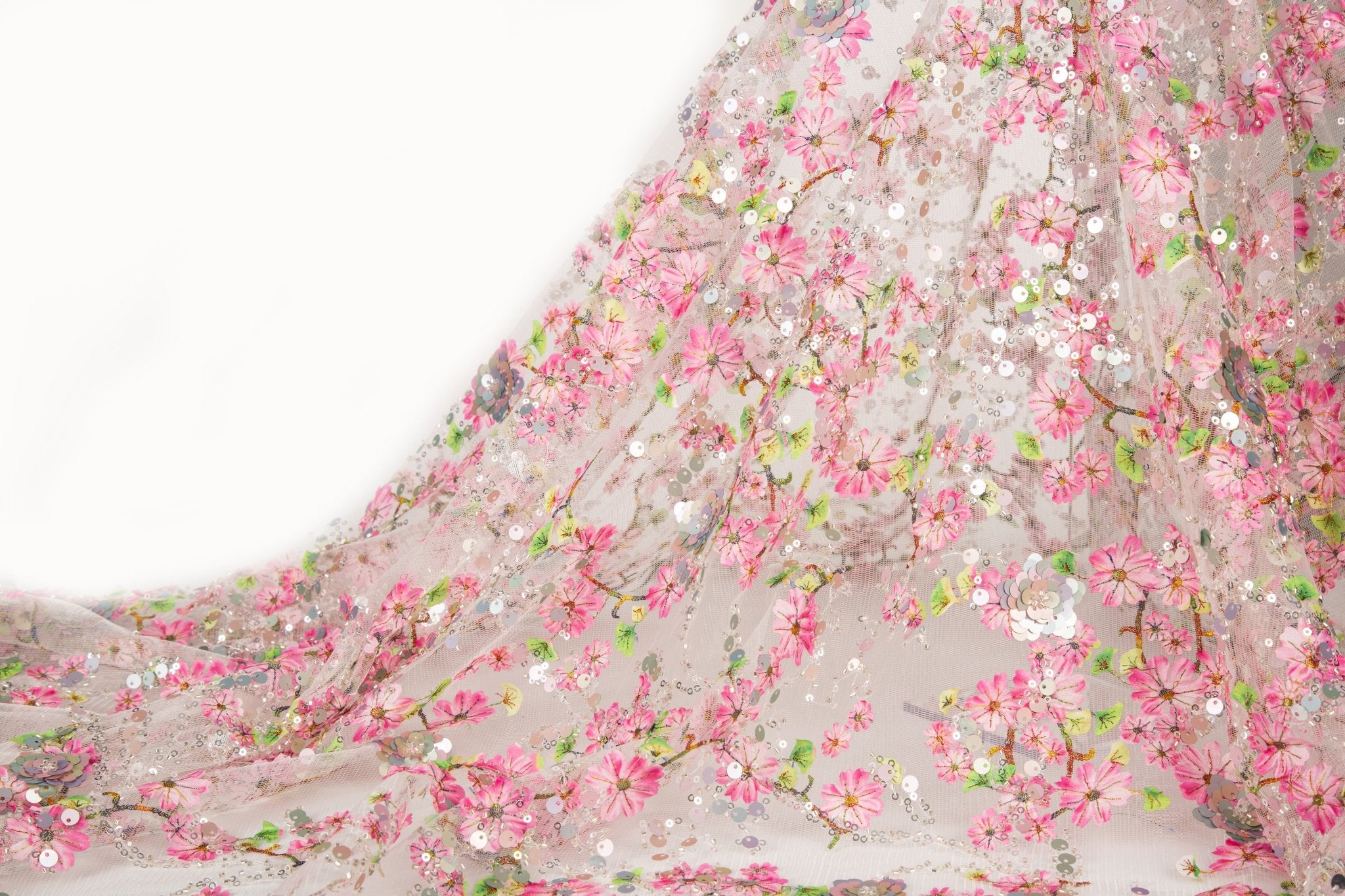 A fine embroidery fabric on white tulle, with a pattern of pink cherry blossom branches and shimmering sequins.
