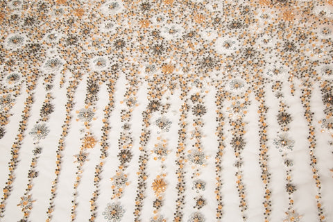 A fine beaded embroidery fabric, with a cascading stardust pattern of vertical lines in champagne gold and pewter.
