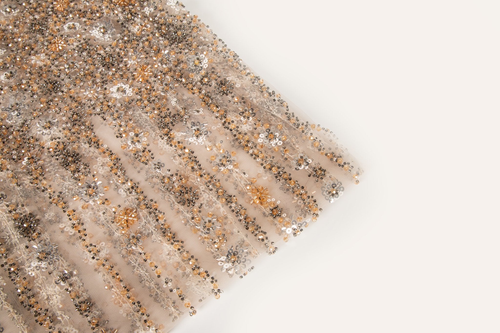 A fine beaded embroidery fabric, with a cascading stardust pattern of vertical lines in champagne gold and pewter.