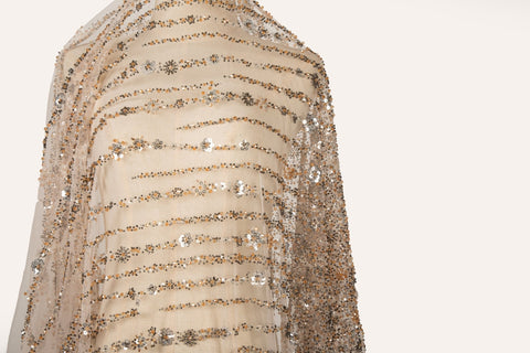 A fine beaded embroidery fabric, with a cascading stardust pattern of vertical lines in champagne gold and pewter.