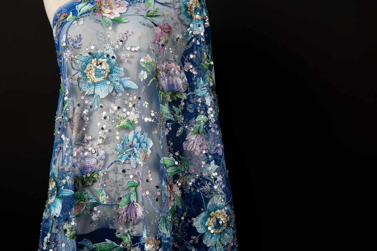 A multi-color floral sequin embroidery fabric on a sapphire blue mesh base.