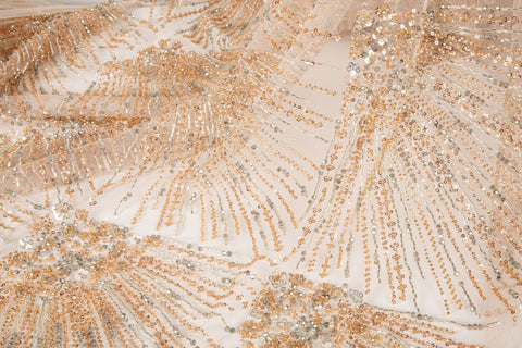 An Art Deco style beaded fabric, with a radiating palm leaf or sunburst pattern in a rose gold and silver palette.

